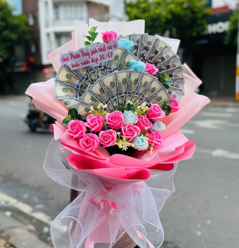 Bó hoa hồng kết hợp tiền và giấy gói màu hồng tạo món quà độc đáo, bắt mắt. (Nguồn: Internet)