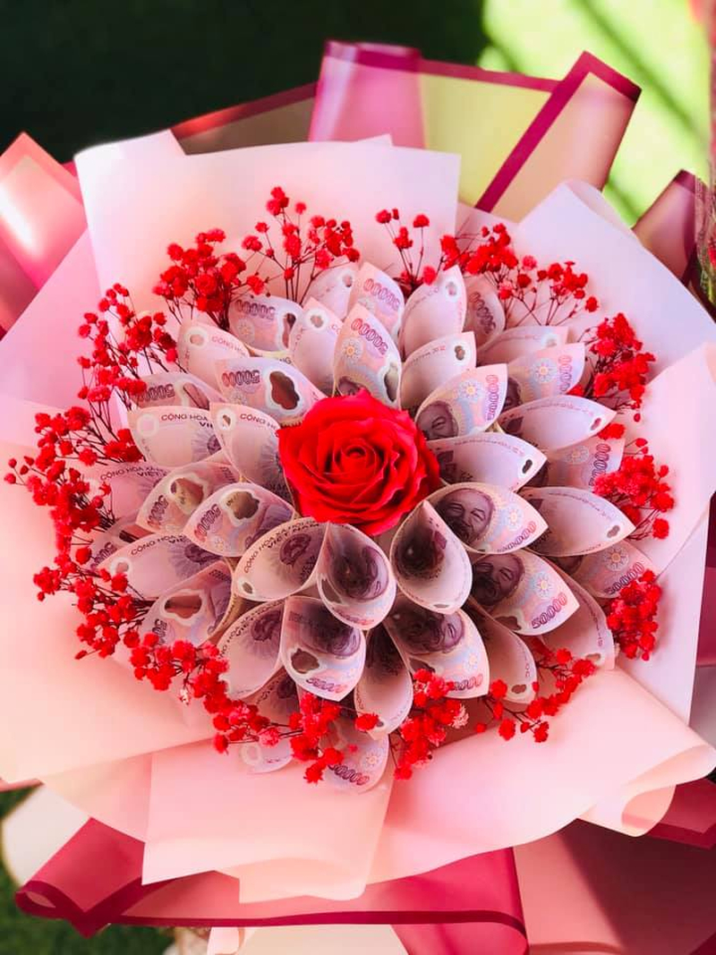 Bó hoa tiền điểm một bông hồng đỏ ở trung tâm, phù hợp với người yêu thích món quà độc đáo. (Nguồn: Internet)