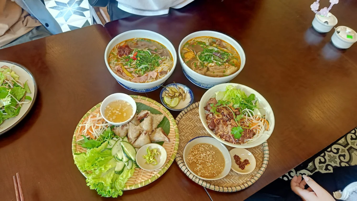 Quán Nón Huế gây ấn tượng với không gian rộng rãi, bàn ghế gỗ mộc mạc và trang trí theo phong cách Huế xưa