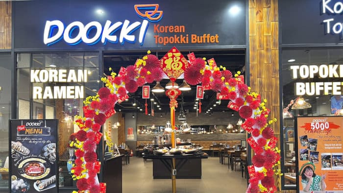 Biển hiệu nhà hàng Dookki tại Central Park Mall với thiết kế hiện đại, nổi bật và quảng cáo các món lẩu hấp dẫn.
