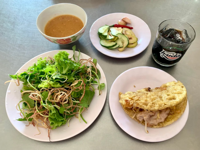 Bánh xèo miền Trung giòn rụm, kèm dĩa rau sống tươi mát và nước chấm đặc biệt, tạo nên bữa ăn chuẩn vị.