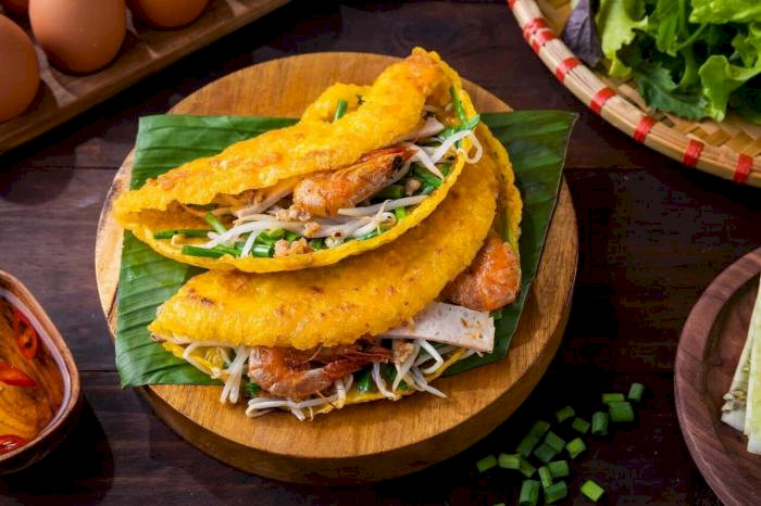 Bánh xèo vàng ươm giòn rụm, đầy đặn nhân tôm thịt, được bày trên lá chuối xanh mát.