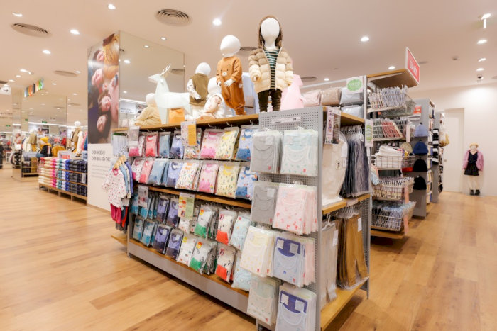 Khu vực trưng b&agrave;y đồ trẻ em, đồ l&oacute;t v&agrave; phụ kiện tại UNIQLO trong AEON Mall Huế, với s&agrave;n gỗ v&agrave; &aacute;nh s&aacute;ng