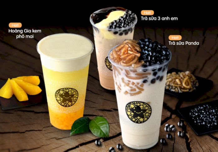 Ba cốc trà sữa TocoToco hấp dẫn với nhiều loại topping trên bàn gỗ.