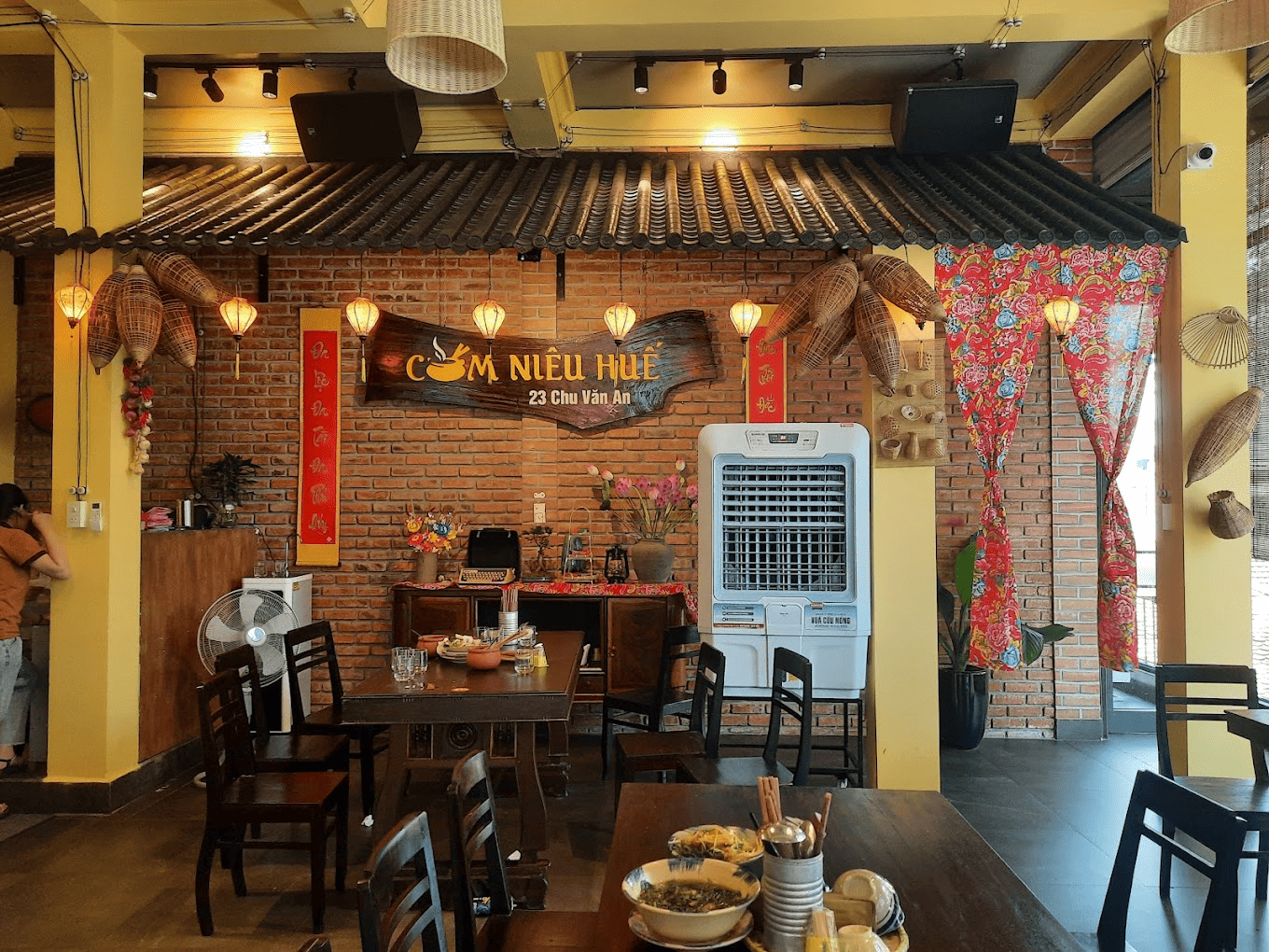 Không gian ấm cúng, mang đậm hơi thở Huế tại Cơm niêu Huế - Urban Không gian ấm cúng của nhà hàng Cơm Niêu Huế với mái ngói, tường gạch, đèn lồng và các vật trang trí mang đậm nét Huế