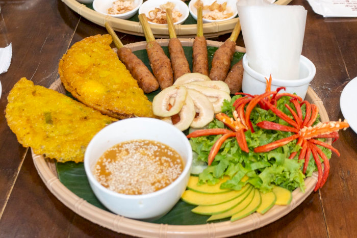 Mâm khai vị Việt Nam thịnh soạn với bánh xèo giòn, nem lụi thơm ngon và rau sống tươi mát.